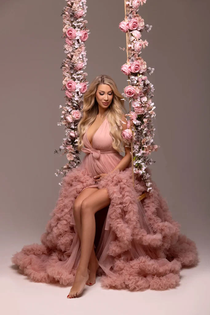 babybauchshooting mit tüllkleid rosa und blumen schaukelnd