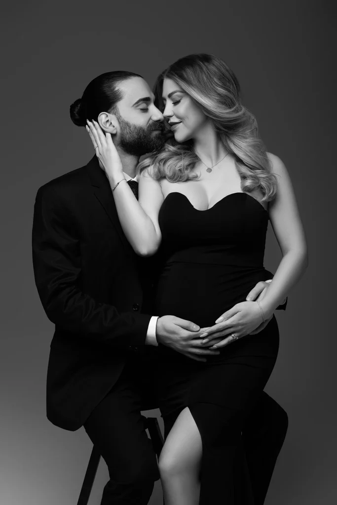 Zeigt ein schwarz weiß Foto von einem innigen Pärchen bei einem Babybauchshooting in einem Studio bei Frankfurt